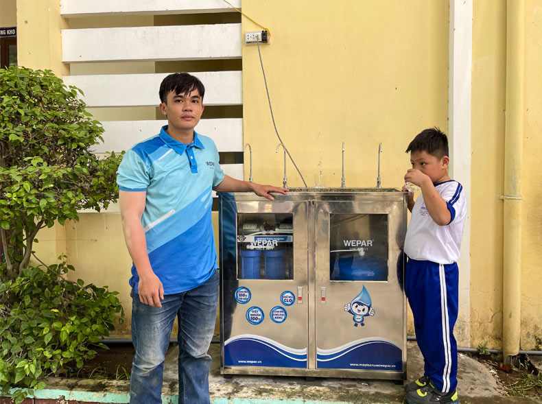 Các em học sinh thử nước uống trực tiếp tại máy lọc nước.